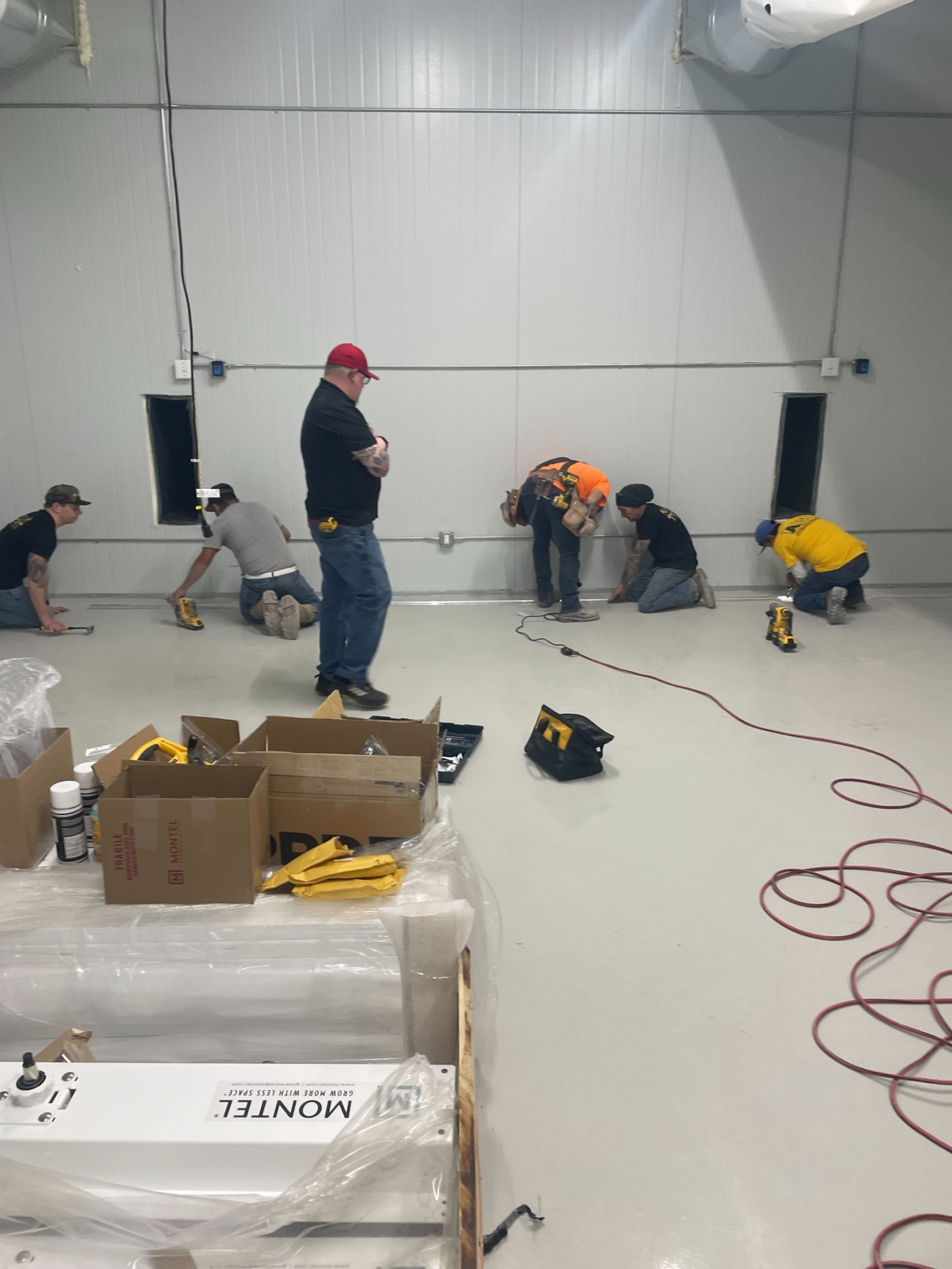 Crew installing wall trim and finish work along the room perimeter