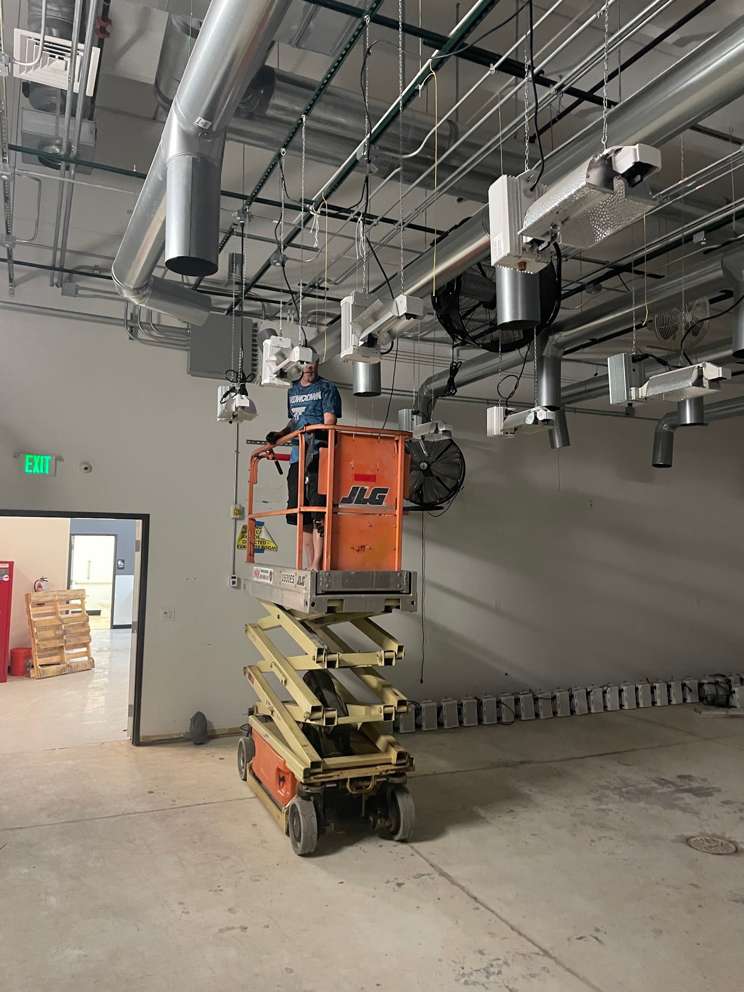 Crew installing overhead ducting from scissor lift